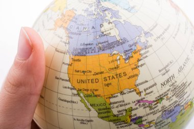 Üzerinde harita olan bir küreyi tutan el.