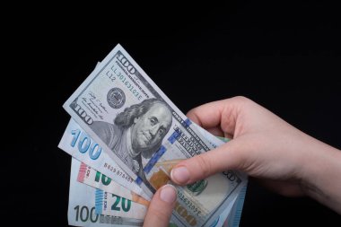 El ele tutuşan Amerikan doları banknotları siyah arka planda izole edilmiş.