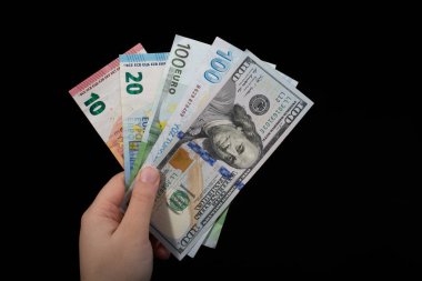 El ele tutuşan Amerikan doları banknotları siyah arka planda izole edilmiş.