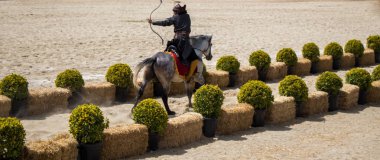 Osmanlı okçusu ata biner ve at sırtında ateş eder.