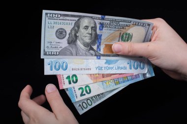 El ele tutuşan Amerikan doları banknotları siyah arka planda izole edilmiş.