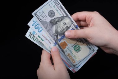 El ele tutuşan Amerikan doları banknotları siyah arka planda izole edilmiş.