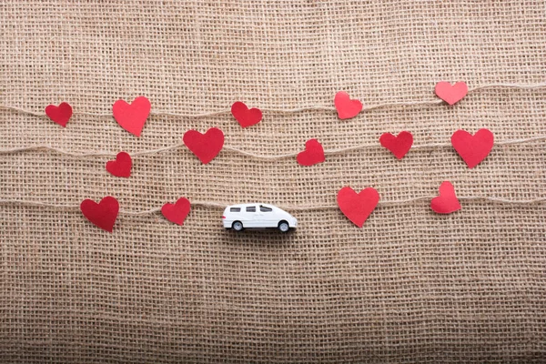 Love concept with car and paper heart on linen threads