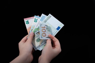 El ele tutuşan Amerikan doları banknotları siyah arka planda izole edilmiş.