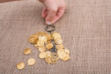 Sahte altınlar üzerinde retro stil bir anahtar tutan el.