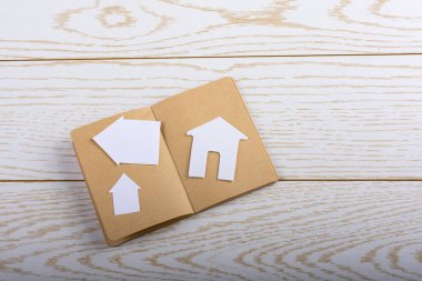 Bir defter parke üzerinde küçük kağıt ev