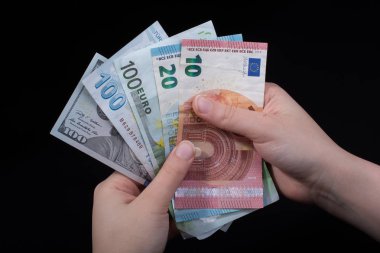 El ele tutuşan Amerikan doları banknotları siyah arka planda izole edilmiş.