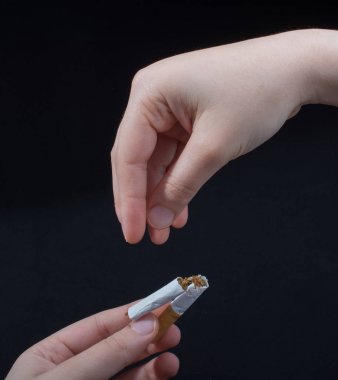 El siyah arka planda sigara kırıyor.