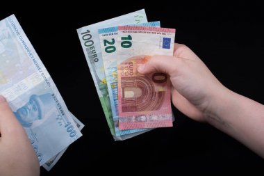 El ele tutuşan Amerikan doları banknotları siyah arka planda izole edilmiş.