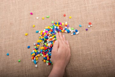 Elindeki ve yerdeki renkli çakıl taşları