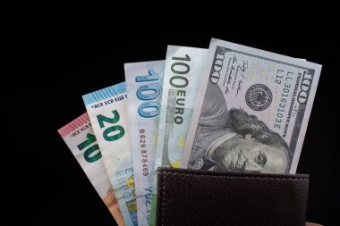 El ele tutuşan Amerikan doları banknotları siyah arka planda izole edilmiş.