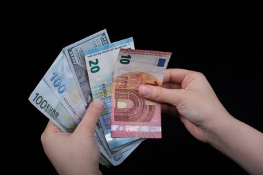 El ele tutuşan Amerikan doları banknotları siyah arka planda izole edilmiş.