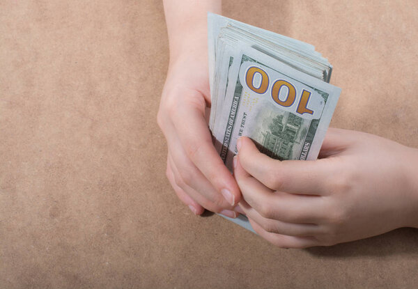 Hand holding American dollar  banknotes isolated on wooden background
