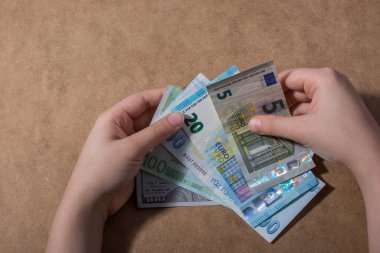 El ele tutuşan Amerikan doları banknotları ahşap arka planda izole edilmiş.