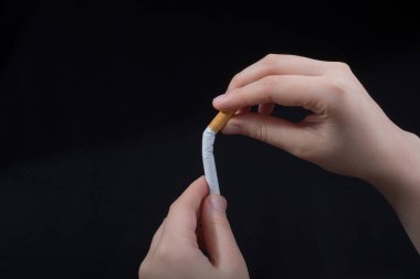 El siyah arka planda sigara kırıyor.
