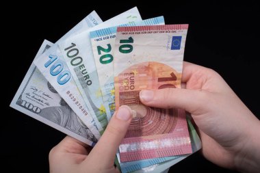 El ele tutuşan Amerikan doları banknotları siyah arka planda izole edilmiş.