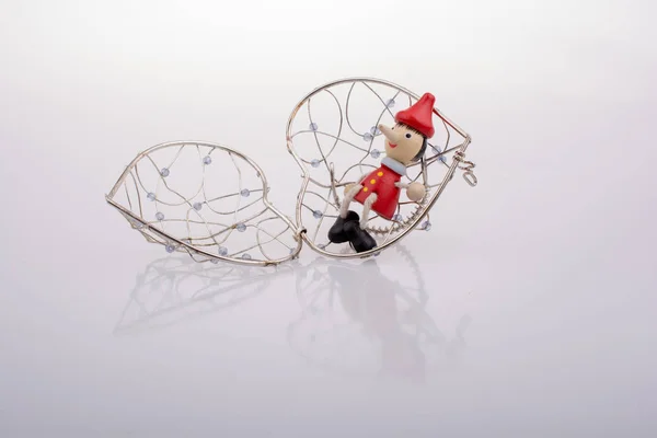 Muñeca Pinocho sentada en una jaula en forma de corazón — Foto de Stock
