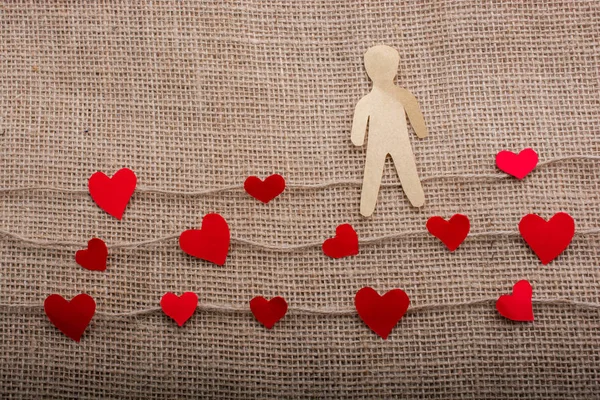 Paper man and heart icons on linen threads on canvas