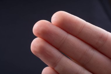 Bir çocuğun üç parmağı kısmen siyah arkaplanda görülüyor