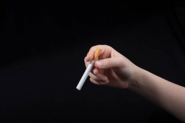 El siyah arka planda bir sigara tutuyor.