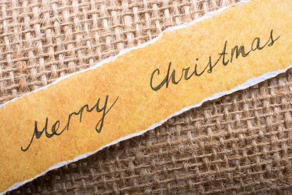 在画布上的撕纸上写上圣诞快乐的措辞 图库图片