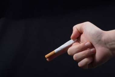 Bir sigara gibi siyah arka plan üzerine silah tutan el