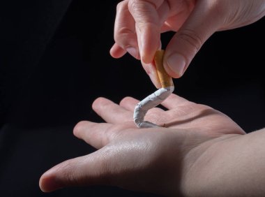 El siyah arka planda sigara kırıyor.