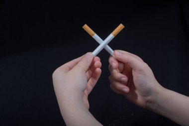 El, siyah arka planda çapraz sigara tutuyor.