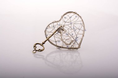 Key and a heart shaped metal cage on white clipart