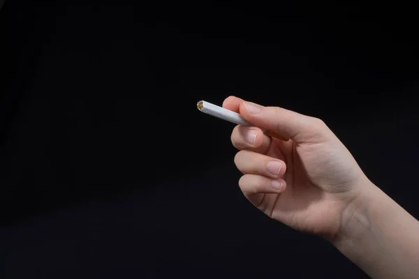 Рука держит сигарету на черном фоне — стоковое фото