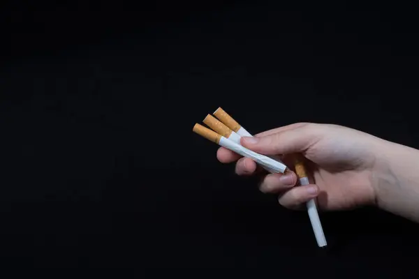 Handen med cigaretter på svart bakgrund — Stockfoto