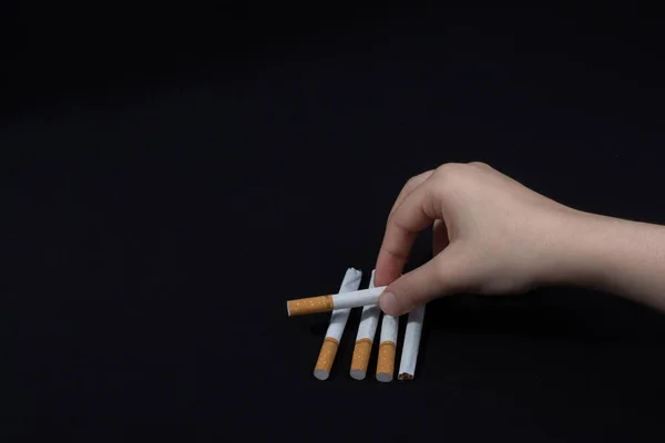Mão está segurando um cigarro no fundo preto — Fotografia de Stock