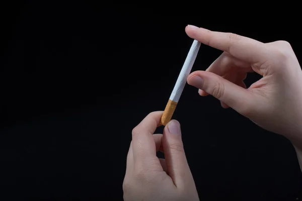 La mano está rompiendo un cigarrillo sobre fondo negro — Foto de Stock