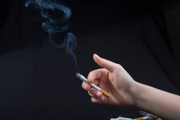 Handen med rökning cigarett på svart bakgrund — Stockfoto