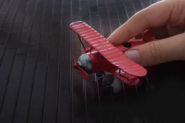 木製のテクスチャ上に赤いおもちゃの飛行機を保持手 — ストック写真