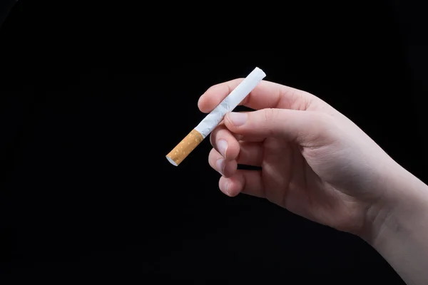 Handen håller cigarett på svart bakgrund — Stockfoto