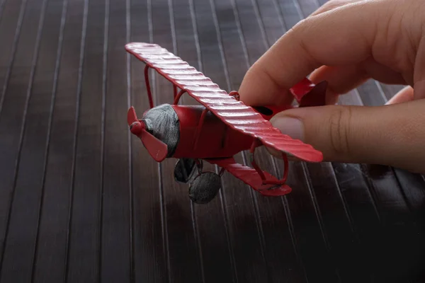 Mano sosteniendo un avión de juguete en textura de madera — Foto de Stock