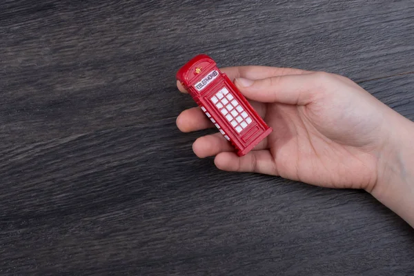 Ręka trzyma czerwone budki telefonicznej — Zdjęcie stockowe