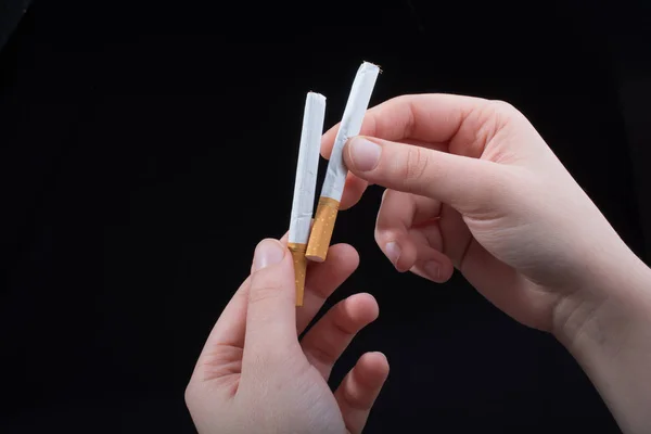 Mão está segurando cigarros no fundo preto — Fotografia de Stock