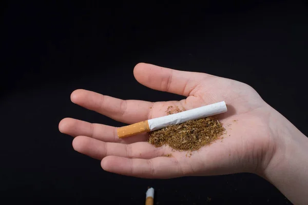 Hand håller en cigarett på svart bakgrund — Stockfoto