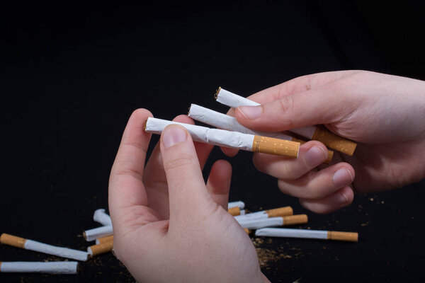 Рука держит сигареты на черном фоне
