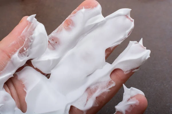 Shaving foam on a hand on dark  background