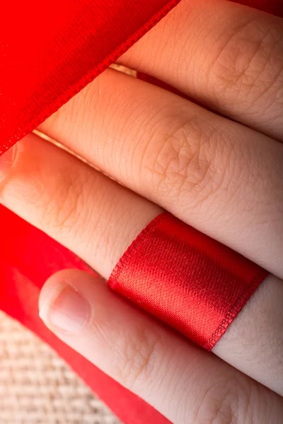 Red string tied around ring finger