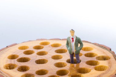 Küçük adam heykelcik ahşap kütük üstünde yerleştirir