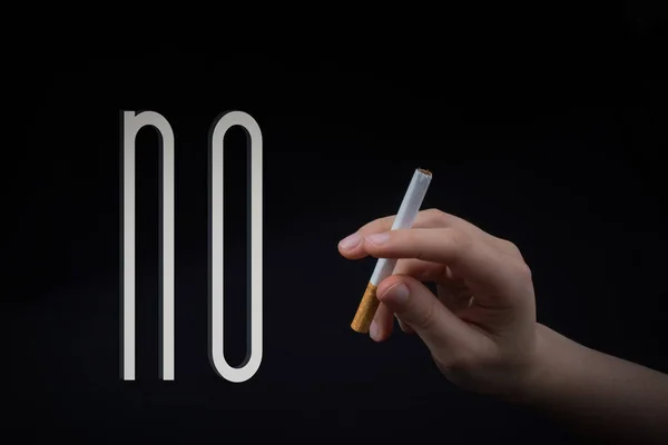 Hand houdt een sigaret vast op zwarte achtergrond. — Stockfoto