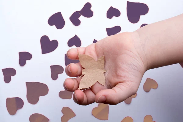 Paper butterfly and paper hearts in hand