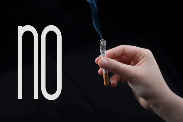 Hand houdt roken sigaret op zwarte achtergrond — Stockfoto