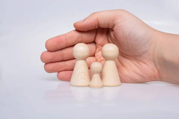 Hand protecting wooden figurines of people as family concept — 图库照片