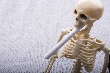 Human skeleton model posing with cigarette in mauth for medical 