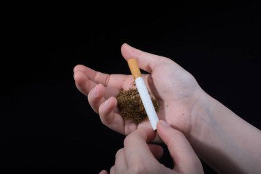 El siyah arka planda bir sigara tutuyor.
